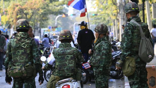 Soldaten in Tarnuniform stehen auf einer Straße in Thailand.