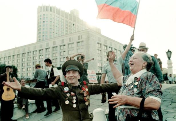 Eine Menschenmenge feiert mit einer russischen Flagge vor einem großen Gebäude.