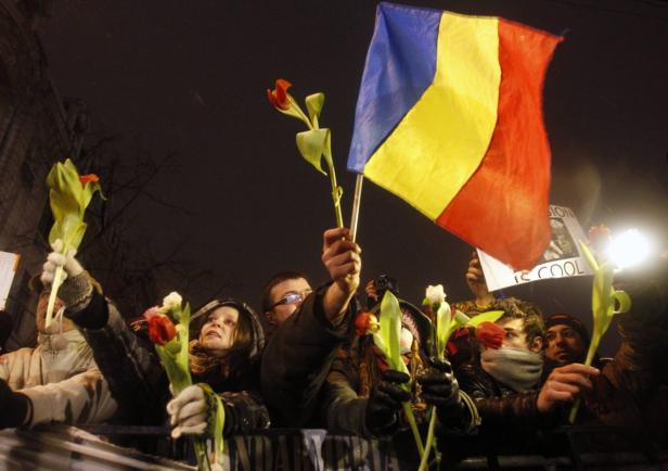 Menschen demonstrieren mit rumänischen Flaggen und Tulpen in der Hand.