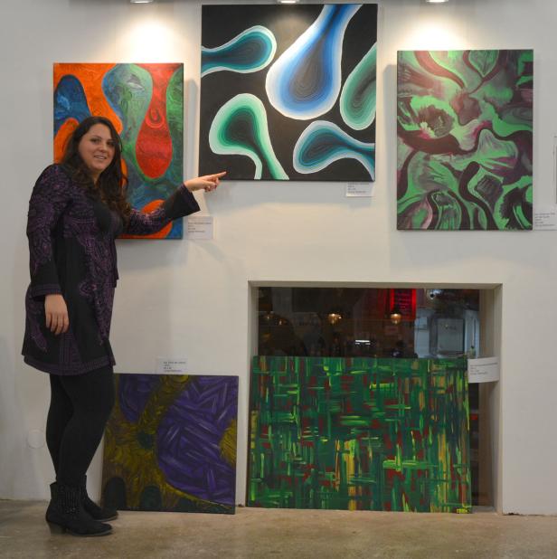 Eine Frau präsentiert eine Ausstellung mit abstrakten Gemälden.
