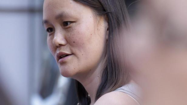 Soon-Yi Eine Frau mit Sommersprossen schaut aufmerksam zur Seite.