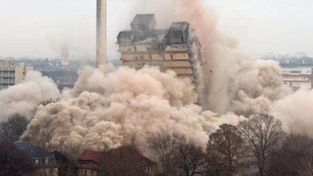 Ein Gebäude wird gesprengt, eine Staubwolke steigt auf.