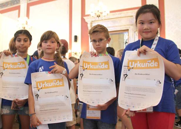 Eine Gruppe Kinder hält Urkunden der Kinderuni Wien in die Kamera.