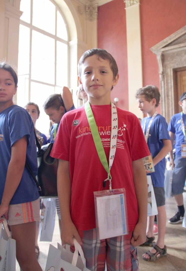 Ein Junge mit rotem T-Shirt und Teilnehmerausweis steht in einer Gruppe von Kindern.