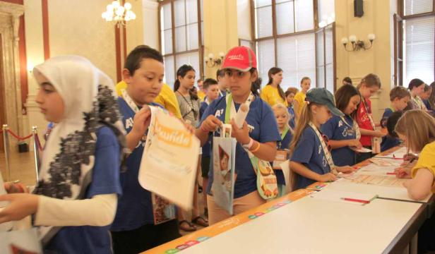 Eine Gruppe von Kindern steht an einem Tisch und nimmt an einer Veranstaltung teil.
