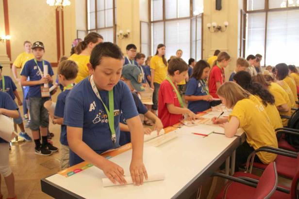 Kinder nehmen an einem Workshop teil und arbeiten an Tischen.