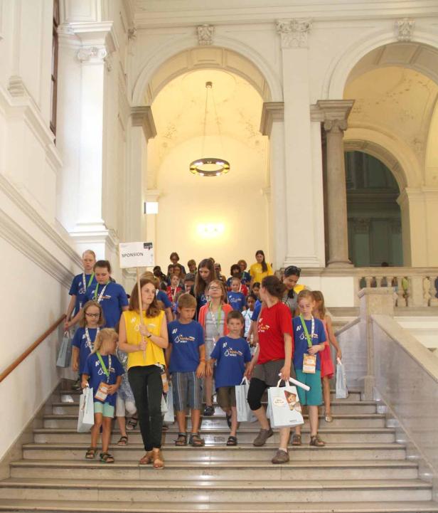 Eine Gruppe Kinder geht eine Treppe in einem hellen Gebäude hinunter.