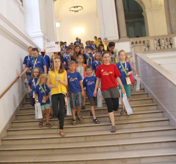 Eine Gruppe Kinder läuft eine Treppe in einem Gebäude hinunter.