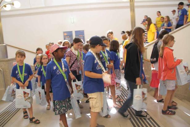 Eine Gruppe Kinder mit blauen T-Shirts und Tragetaschen geht eine Treppe hinunter.