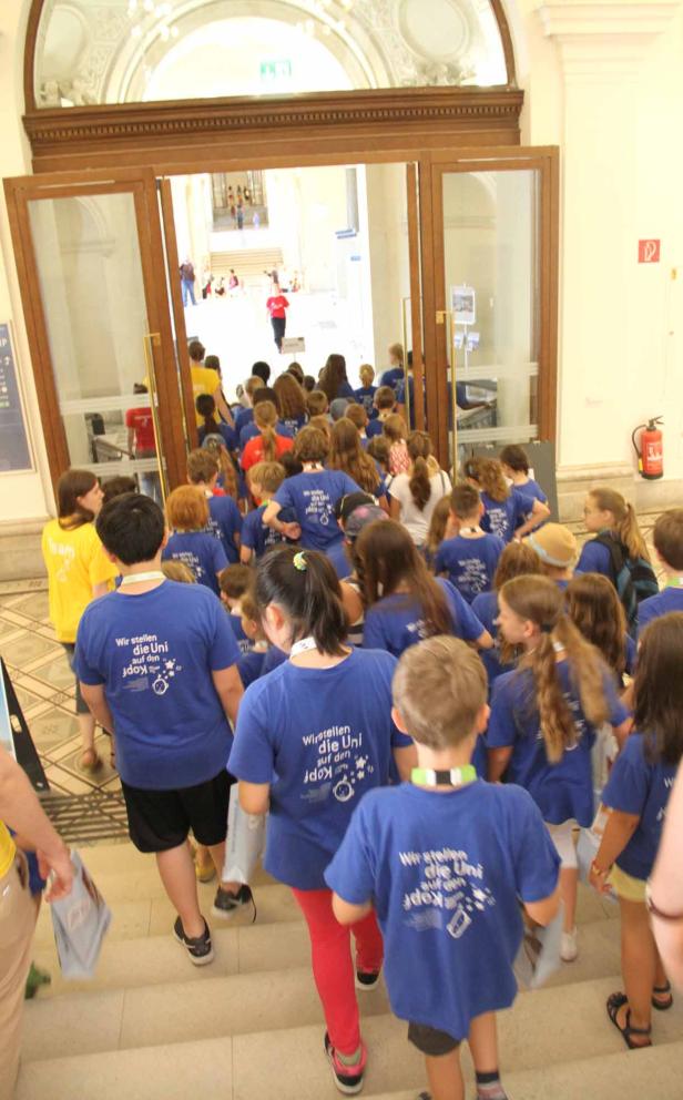 Eine Gruppe Kinder in blauen T-Shirts betritt ein Gebäude.