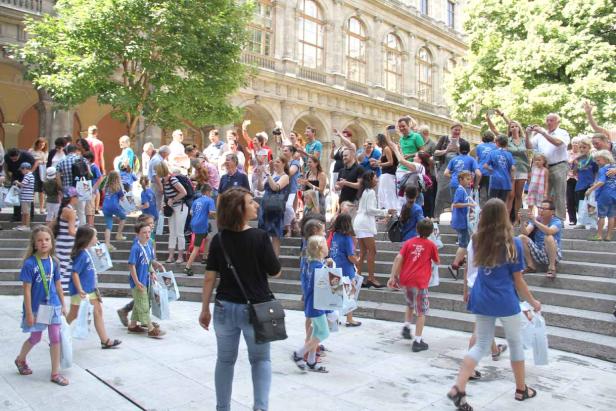 Eine Gruppe von Kindern und Erwachsenen versammelt sich vor einem Gebäude.