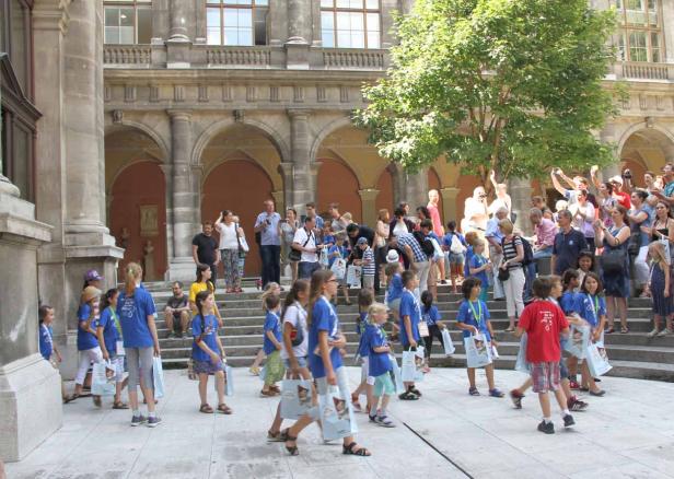Eine Gruppe von Kindern in blauen T-Shirts steht vor einem historischen Gebäude.