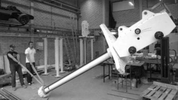 Zwei Männer hantieren an einem großen, weißen Bauteil in einer Werkshalle.