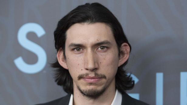 Porträt von Adam Driver vor einem grauen Hintergrund.