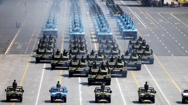 Eine Militärparade mit Panzern und anderen Militärfahrzeugen auf einer breiten Straße.