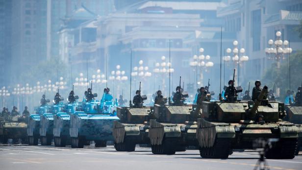 Eine Parade von Panzern fährt durch eine städtische Umgebung.