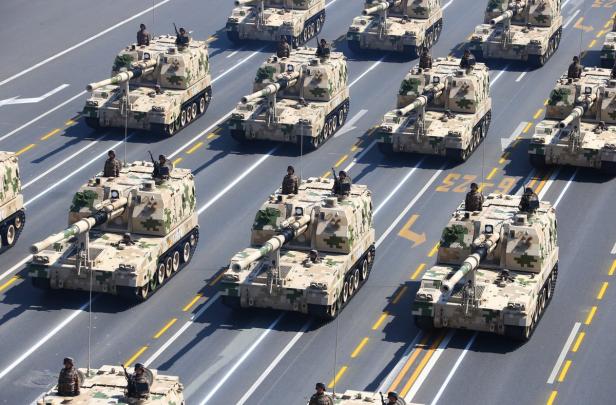 Mehrere Panzer fahren in einer Parade auf einer asphaltierten Straße.