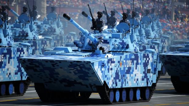 Mehrere blau-weiß getarnte Panzer fahren bei einer Militärparade.