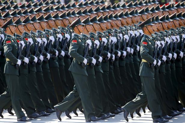Eine Reihe chinesischer Soldaten marschiert in Uniform mit Gewehren.