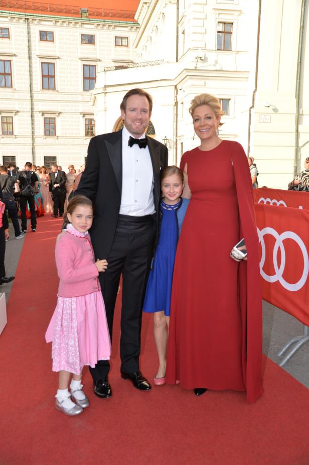 Eine Familie posiert auf einem roten Teppich vor einem Gebäude.