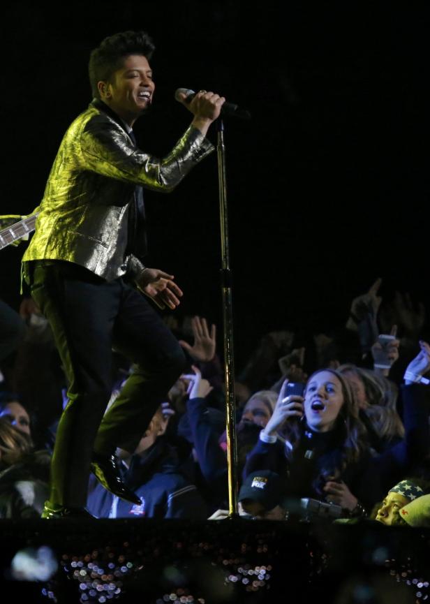 Bruno Mars tritt in einer goldenen Jacke vor einem begeisterten Publikum auf.