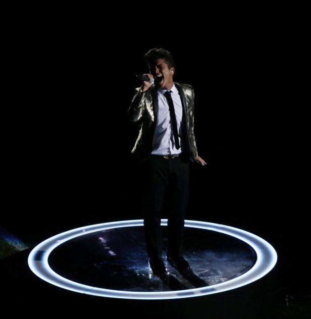 Bruno Mars singt auf einer Bühne mit einem leuchtenden Ring um ihn herum.
