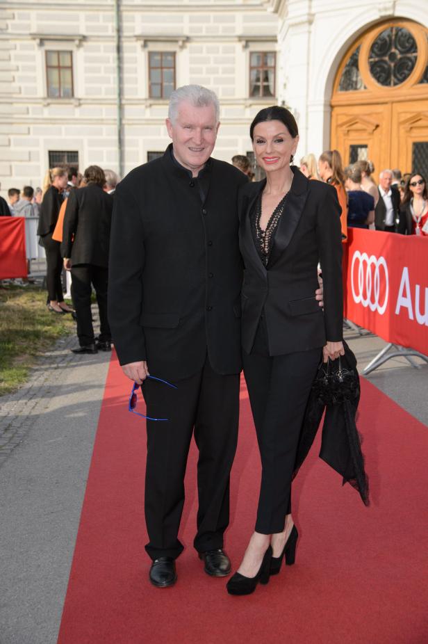 Ein Mann und eine Frau posieren auf einem roten Teppich vor einem Gebäude.