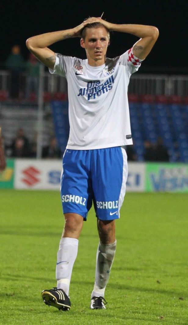Ein Fußballspieler mit blonden Haaren hält sich enttäuscht den Kopf.