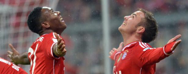 Zwei Fußballspieler des FC Bayern jubeln im Regen.