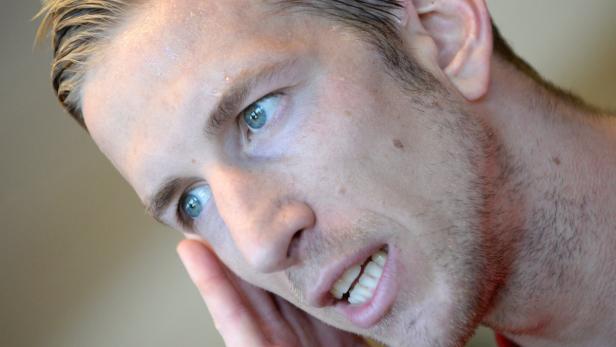 Ein Mann mit hellblauen Augen und blonden Haaren schaut zur Seite.