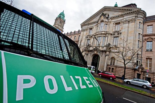 Ein grüner Mannschaftswagen der Polizei vor einem historischen Gebäude.
