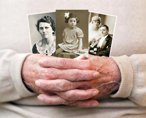 Alte Hände halten drei Schwarzweißfotos von Familienmitgliedern verschiedener Generationen.