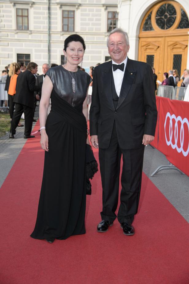 Ein elegant gekleidetes Paar posiert auf einem roten Teppich.