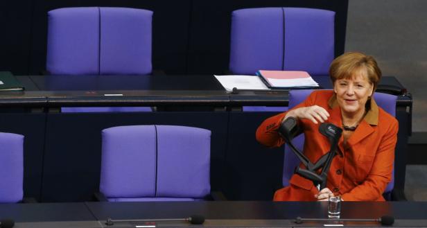 Angela Merkel sitzt mit Krücken im Bundestag.