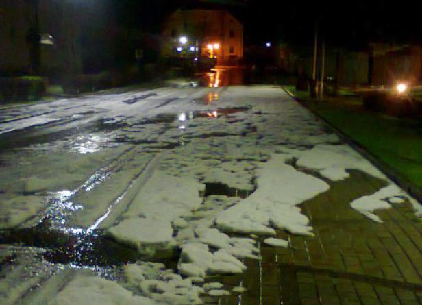 Eine Straße und ein Gehweg sind nachts mit Eis bedeckt.
