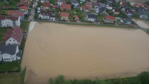 Überschwemmtes Feld neben einer Wohngegend.