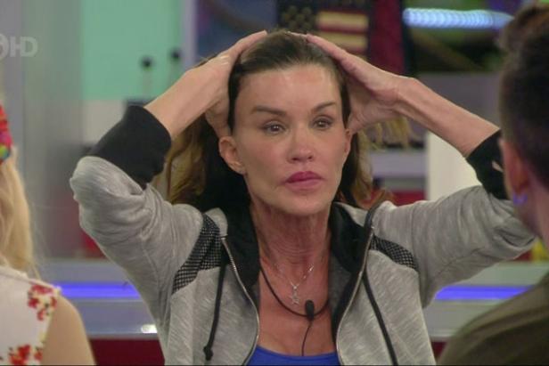 Eine Frau mit grauer Jacke hält ihre Hände an ihren Kopf.