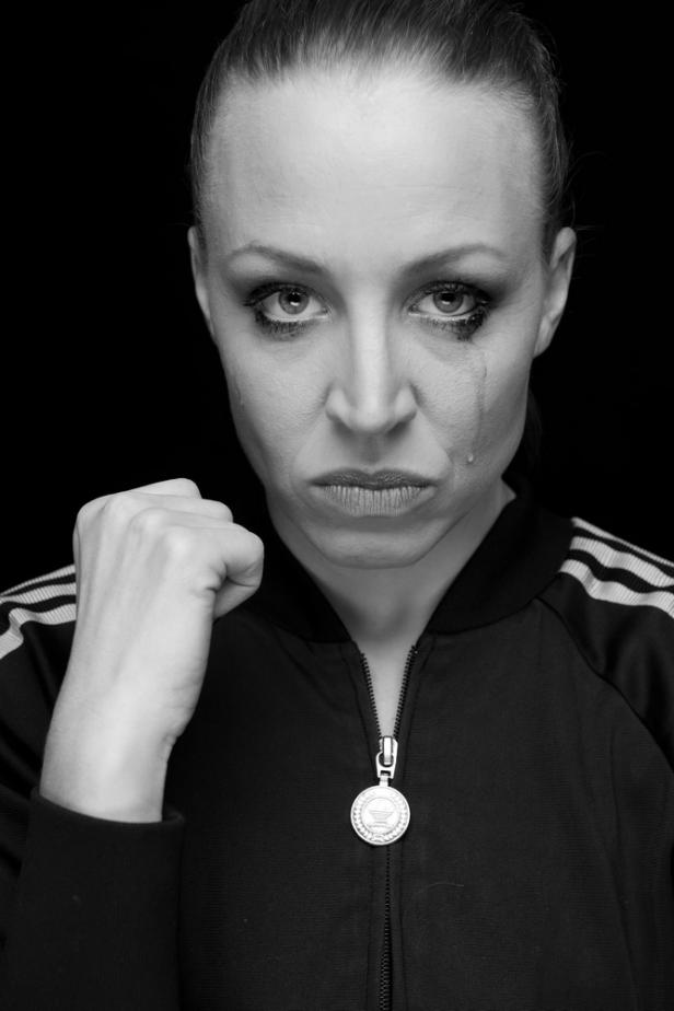 Eine Frau mit Tränen im Gesicht ballt die Faust.