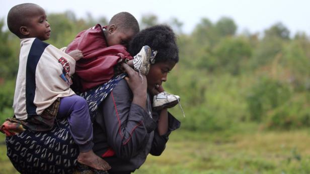 Besonders schwierig ist die Situation in der Demokratischen Republik Kongo Eine Frau trägt zwei Kinder auf dem Rücken durch eine ländliche Gegend.