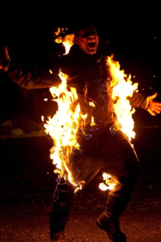 Eine Person steht in Flammen und schreit.