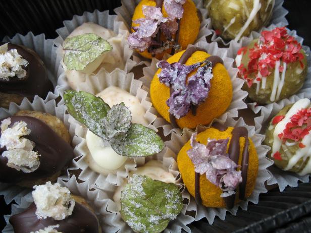 Verschiedene Pralinen und Konfekt in Papierförmchen, dekoriert mit Blüten und Blättern.