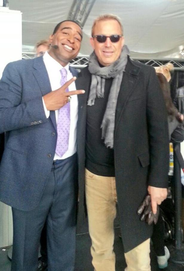 Ein Mann im Anzug posiert mit Kevin Costner für ein Foto.
