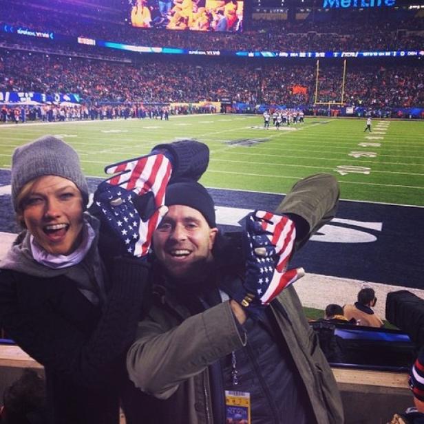 Karlie Kloss und ein Mann mit USA-Handschuhen schauen ein American-Football-Spiel.