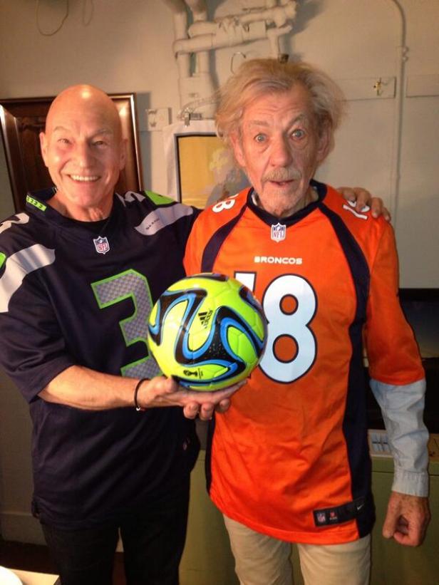 Patrick Stewart und Ian McKellen halten jeweils ein Football-Trikot und einen Fußball.