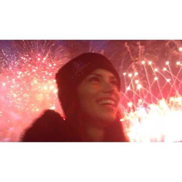 Eine lächelnde Frau vor einem Feuerwerk.