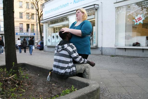 Eine Frau legt einem sitzenden Mann tröstend die Hand auf den Kopf.