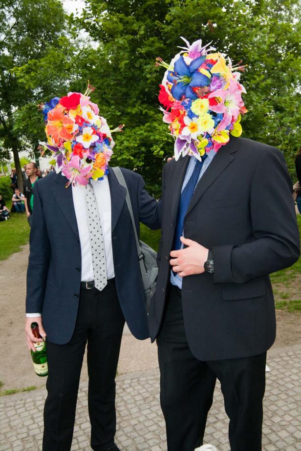 Zwei Männer in Anzügen tragen Blumenmasken.