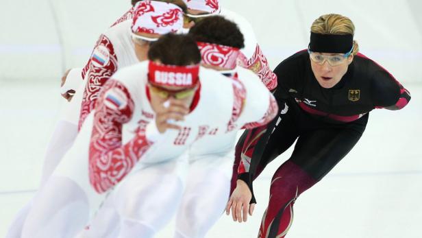 Eine deutsche Eisschnellläuferin im Wettkampf, gefolgt von russischen Athleten.