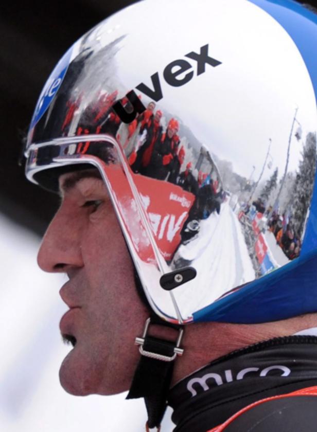 Ein Rennrodler mit einem Uvex-Helm, der die Zuschauermenge reflektiert.