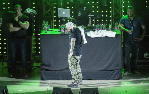 Ein Rapper steht mit einem Handtuch auf dem Kopf auf einer Bühne.